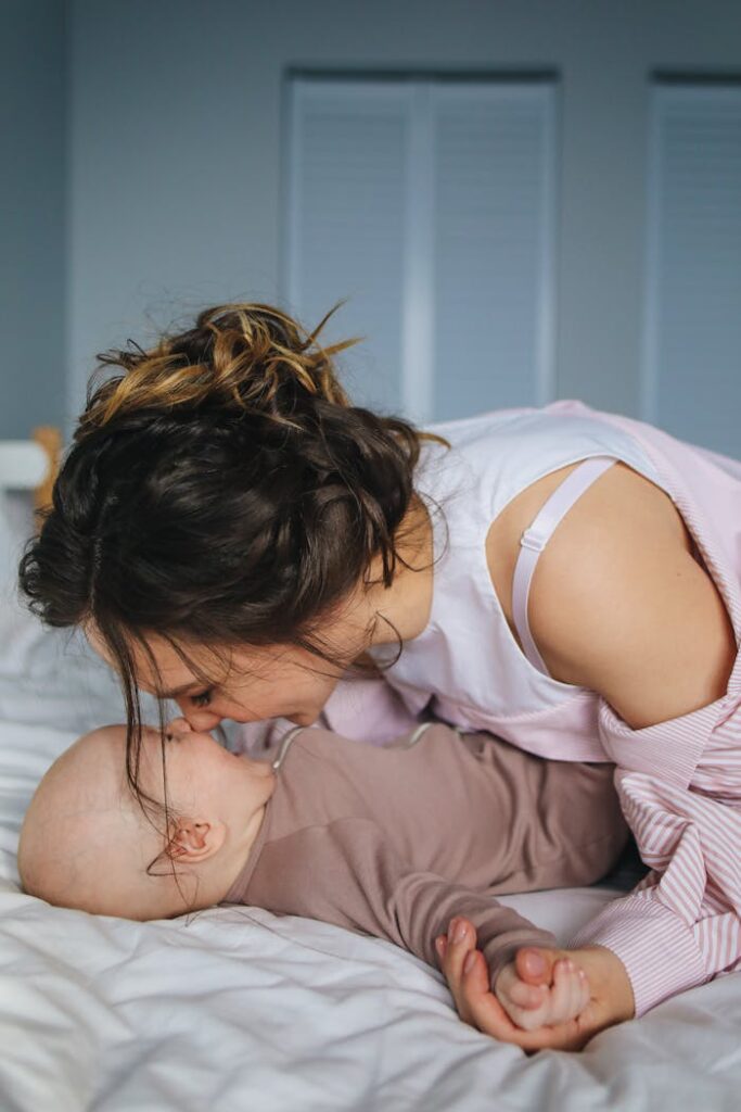 Mother shares a tender moment with her baby, lying together in a cozy and comfortable bedroom.