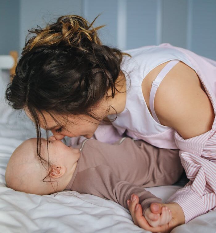 pexels-photo-3875200 Mother shares a tender moment with her baby, lying together in a cozy and comfortable bedroom.